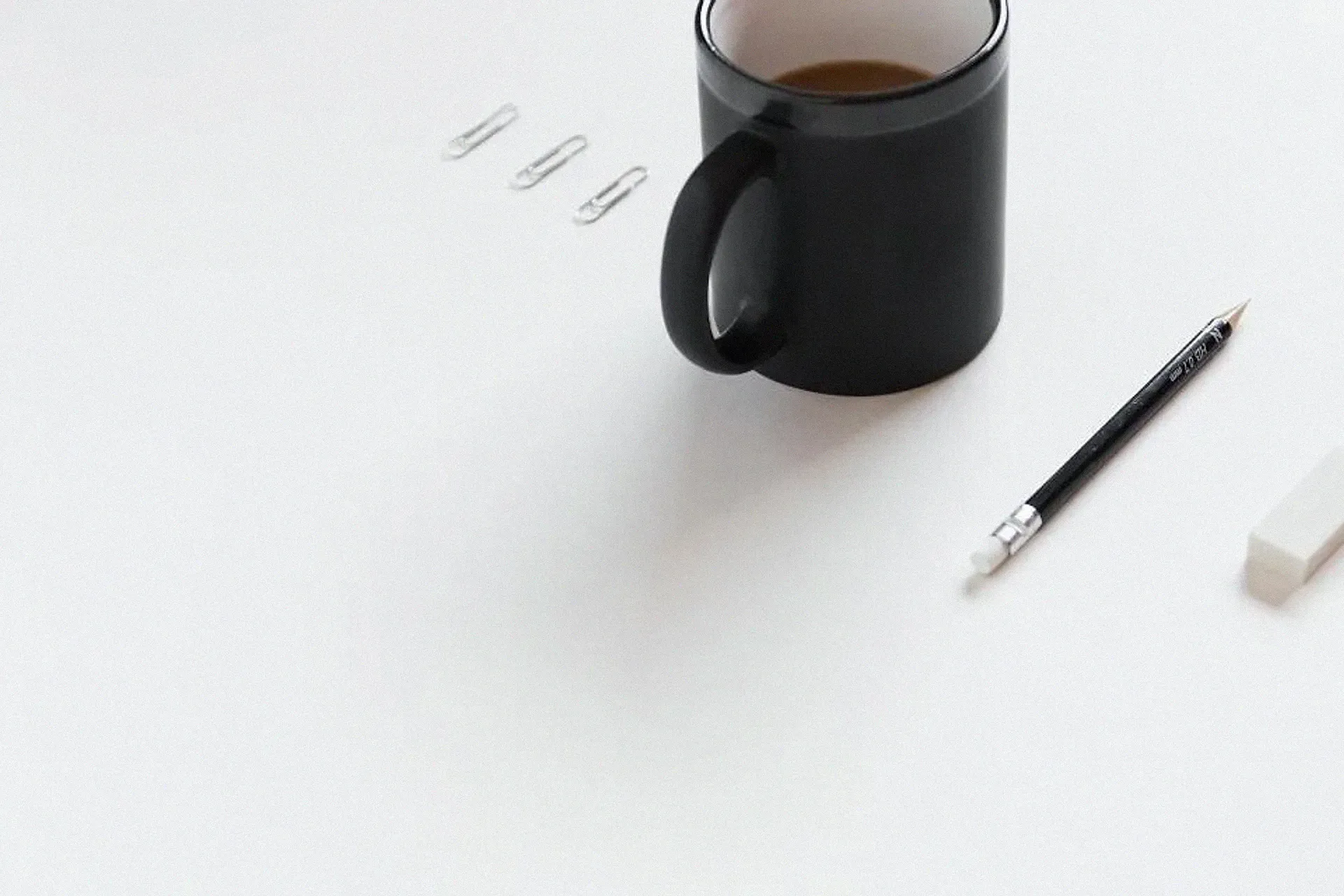 A mug, a pencil and an eraser on a white desk