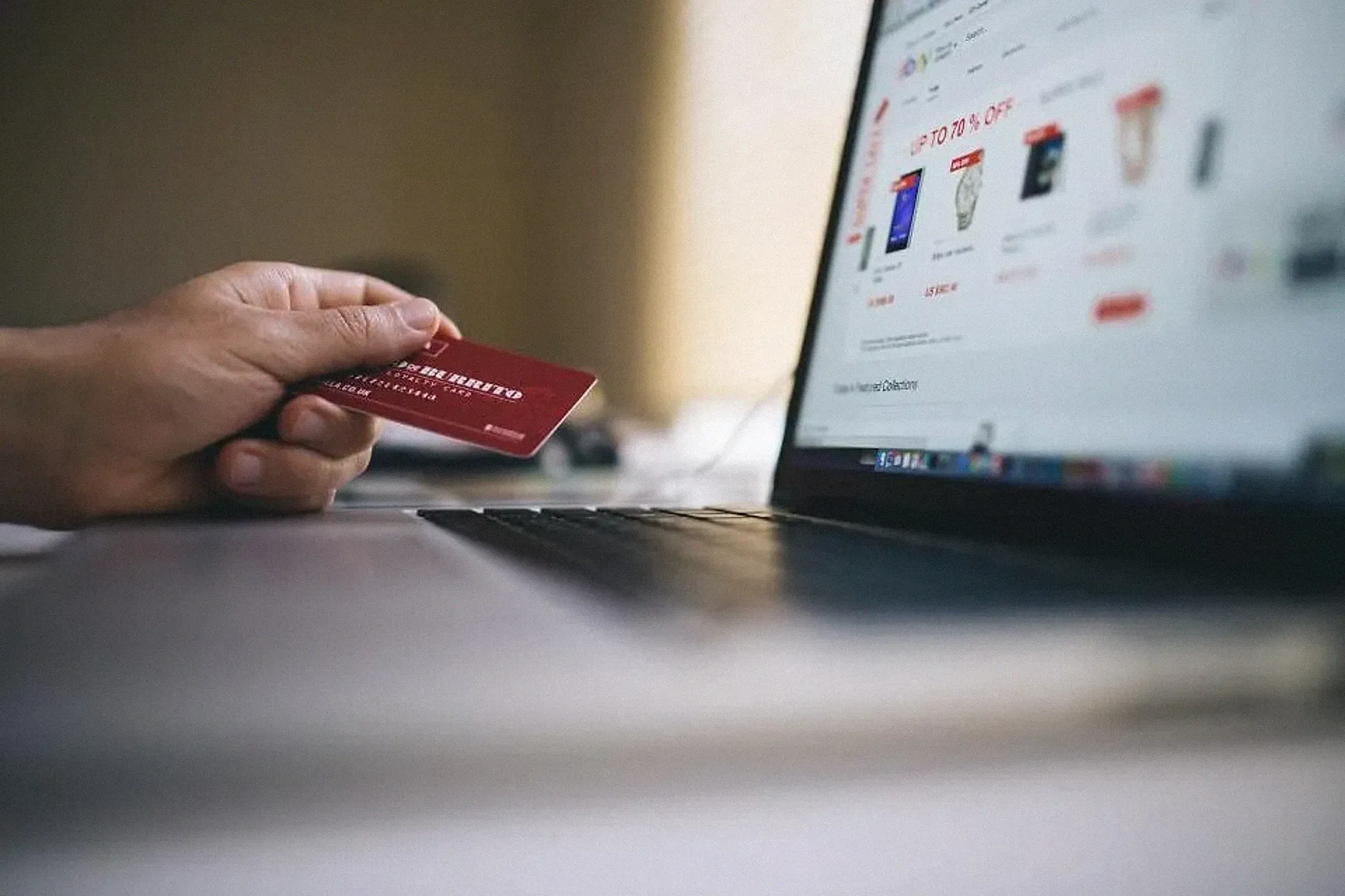 A hand holding a payment card beside a laptop at checkout