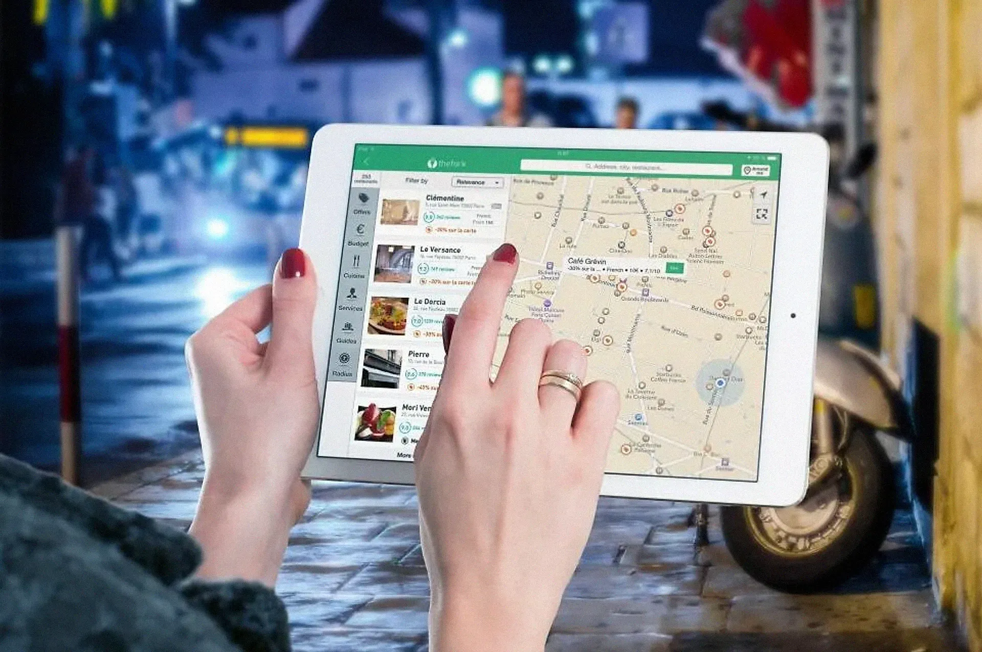 Hands using a tablet showing a local map with place listings