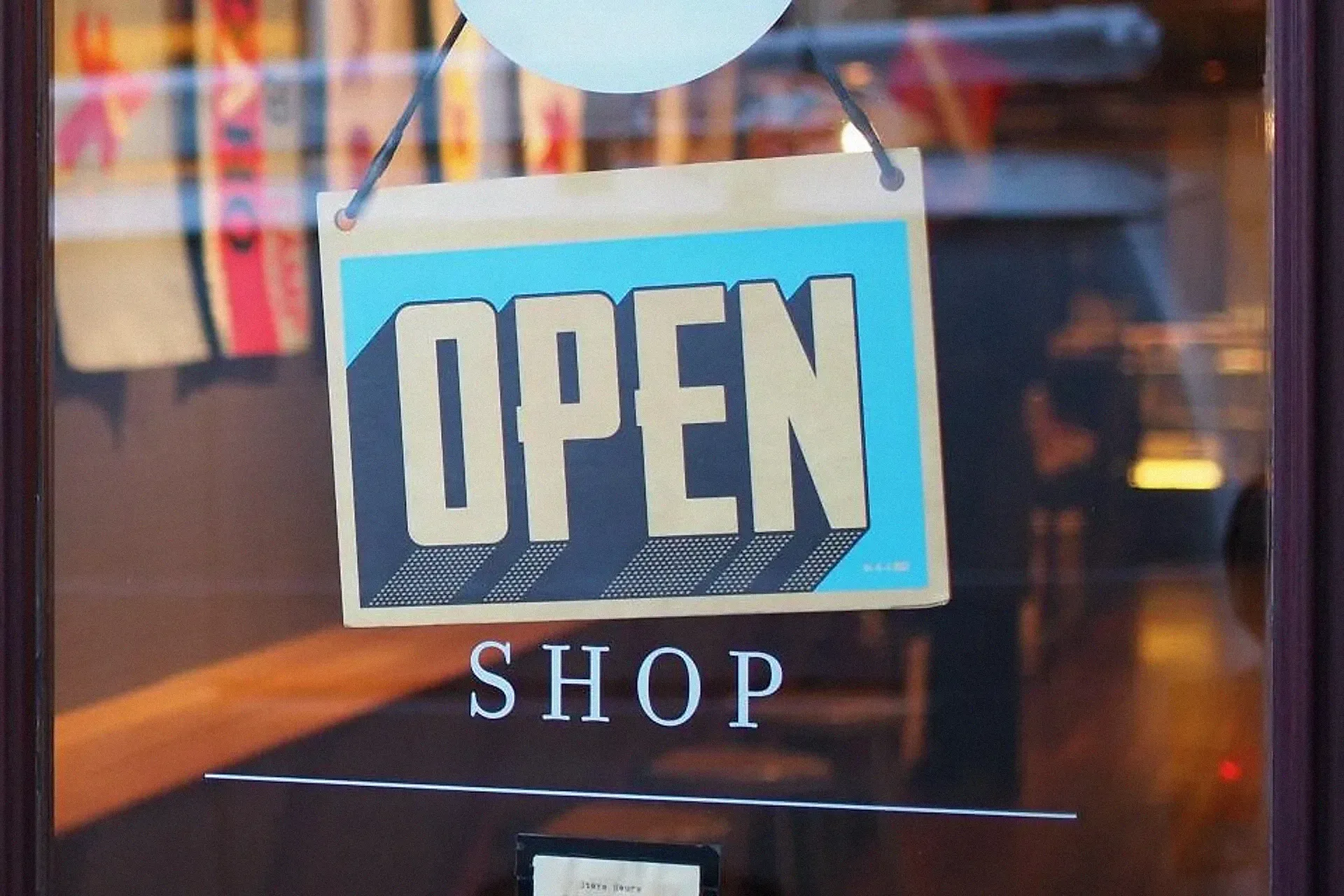 An open sign hanging in a small shop window