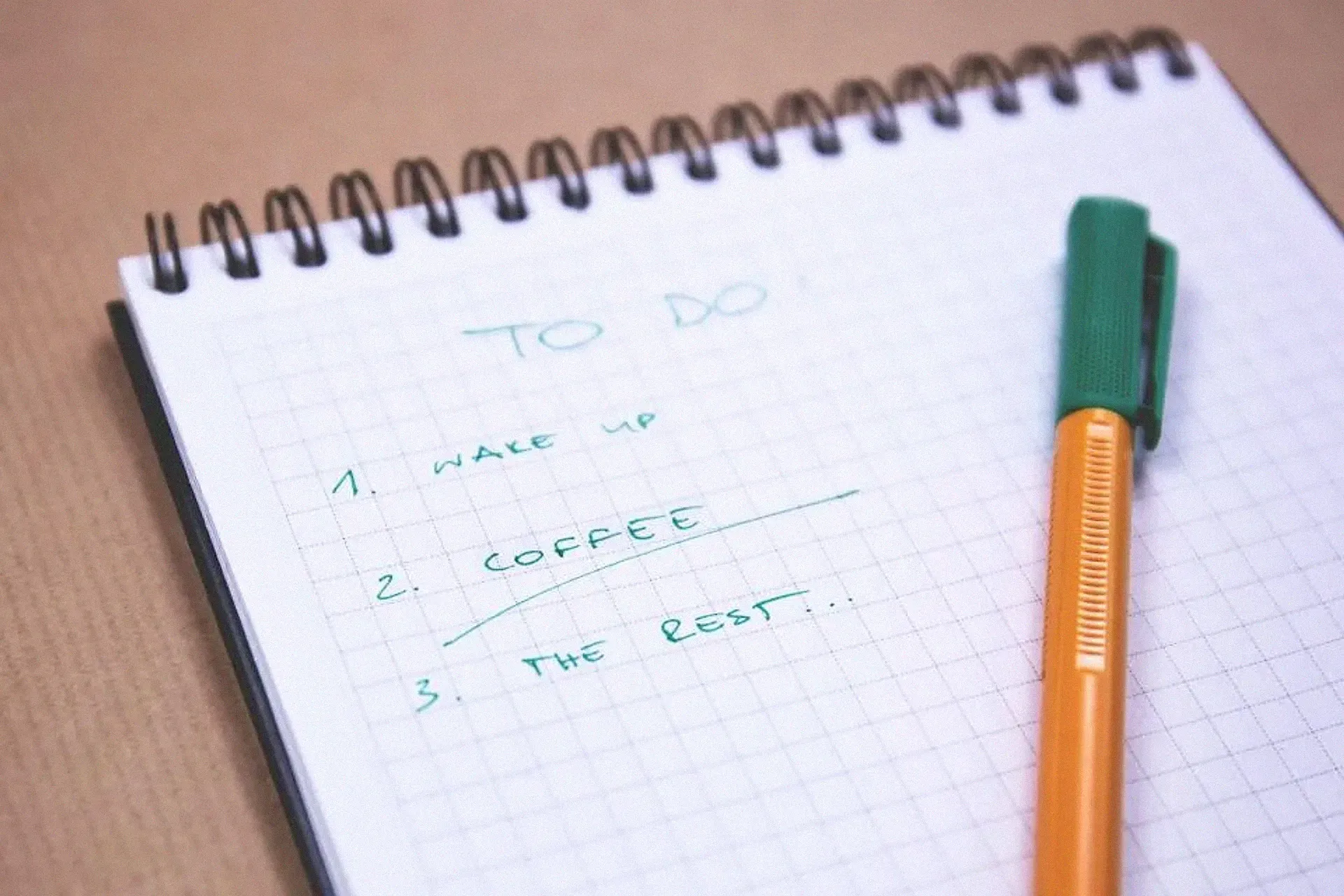 A spiral notebook with a handwritten to-do list and a pen