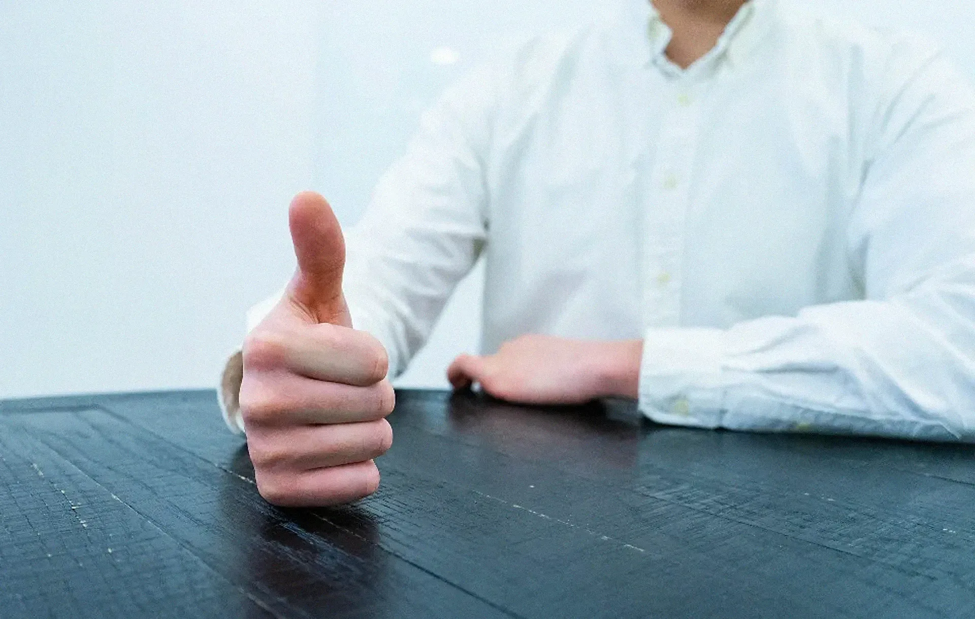 A person giving a thumbs up at a desk