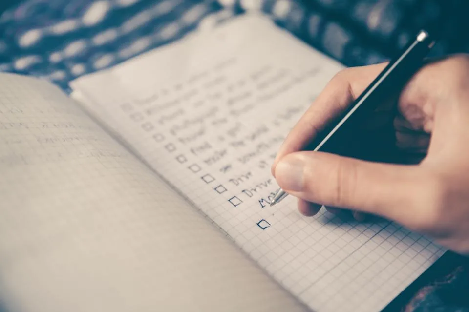 A hand ticking off a checklist in a notebook