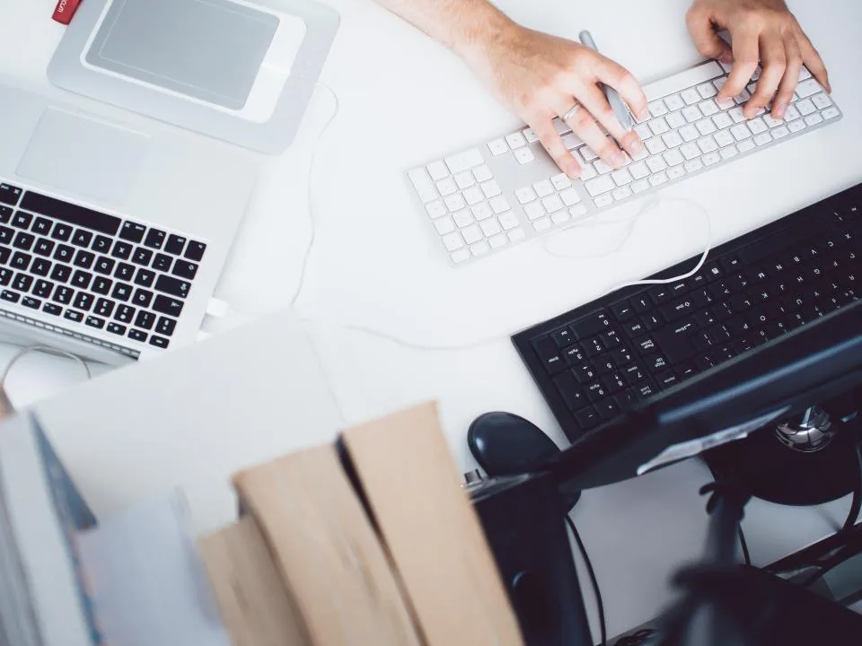 Hands typing on a keyboard beside a laptop