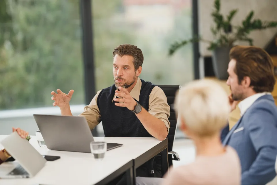 Colleagues talking across a table in a bright office